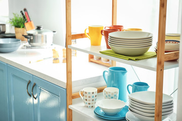 Shelving with different clean dishes in kitchen