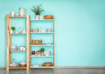 Kitchen shelving with dishes on color wall background