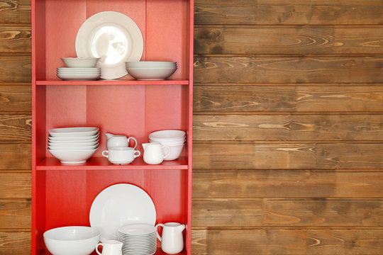 Cupboard with dishes on wooden wall background