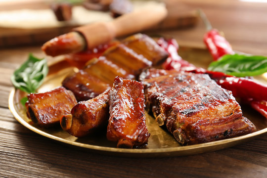 Plate with delicious grilled ribs on table