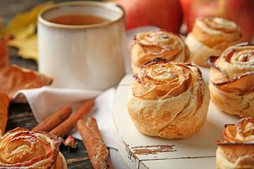Wooden board with apple roses from puff pastry on table, closeup