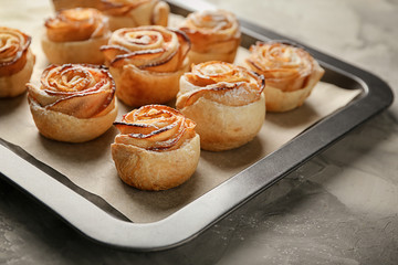 Baking tray with apple roses from puff pastry on table, closeup