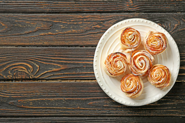 Plate with apple roses from puff pastry on wooden background