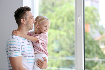 Fototapeta premium Young man with cute little girl near window at home