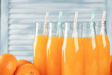 Bottles with fresh citrus juice on on blurred background