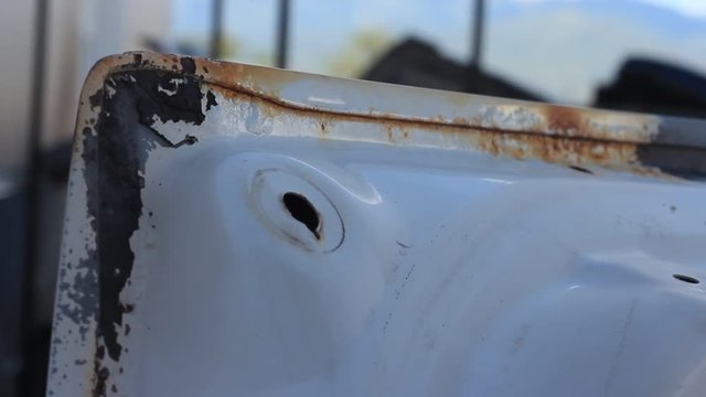 A high pressure sand blaster blows away rust and corrosion from an old car part.