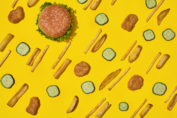 Most popular fast food meal. Chicken nuggets, burger and french fries on yellow background top view