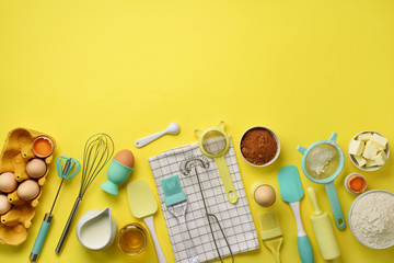 Baking ingredients - butter, sugar, flour, eggs, oil, spoon, rolling pin, brush, whisk, towel over yellow background. Bakery food frame, cooking concept. Top view, copy space. Flat lay