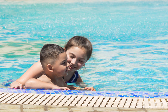 Smiling boy and little girl swimming in pool in aquapark. Summer vacation concept. Space for text