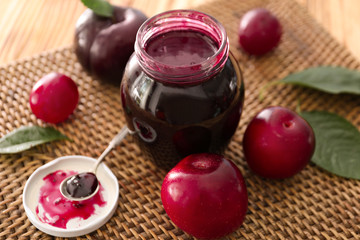 Jar with tasty plum jam on table