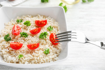 Plate with delicious brown rice and vegetables on table, closeup
