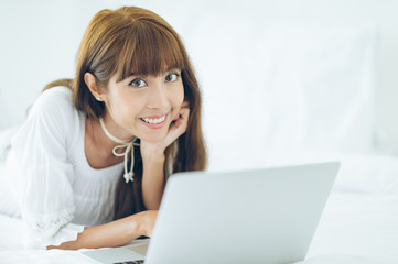 Teenage girl lying on bed using laptop