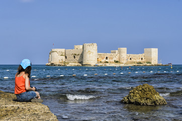 woman watching castle from beach mersin kizkalesi on the rock pier castle in the sea turkey