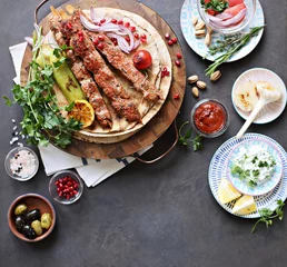 Fototapeten  Kebab. Traditional middle eastern, arabic or mediterranean  meat kebab with vegetables and herbs. Overhead view, copy space © losangela