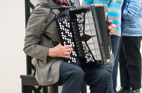 Elderly retired grandfather playing on accordion.
