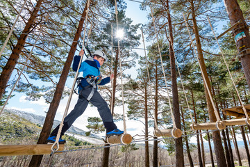 A kid evolves through an obstacle hanging from the trees at an adventure park in Segovia, Spain