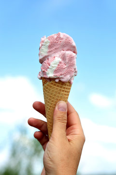 Lody gałkowe w rożku waflowym trzymanym w dłoni.