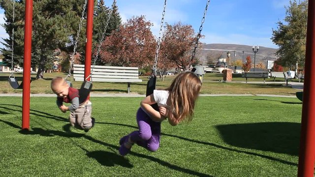 Kids Swinging At The Park Having Fun.