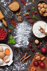 Flour, eggs, spices and fresh berries - ingredients for summer cake. Close-up, Top view on  dark  concrete background.