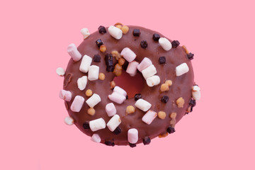 Chocolate doughnut with small marshmallos on a pink bankground