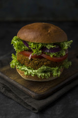 Vegan burger with vegetables on cutting board