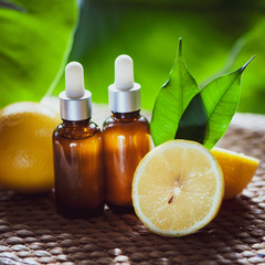 Bottles with lemon oil, fresh  fruit whole and half on a natural tropical background.