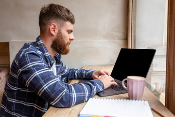 Young man chatting via net-book during work break in coffee shop