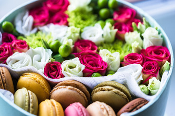 Fototapeta na wymiar flower box with flowers and macarons composition closeup