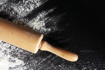 Baking background with the rolling pin with flour. On the dark table. Free space for text