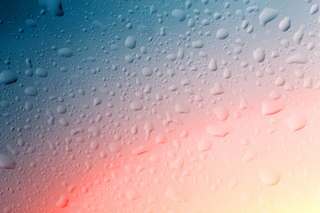 Water drops on window glass surface with red and yellow light