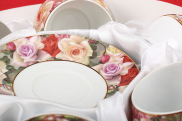 Tea Set with floral pattern in a box with white cloth. Saucers and tea cups