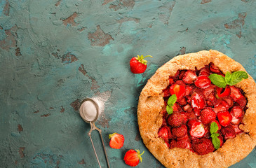 Galette with strawberry on the blue stone background.