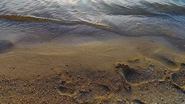 Yellow sand with footprint and slow motion of waves from sea closeup