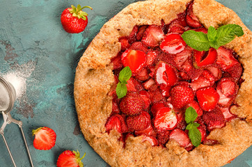 Galette with strawberry on the blue stone background.