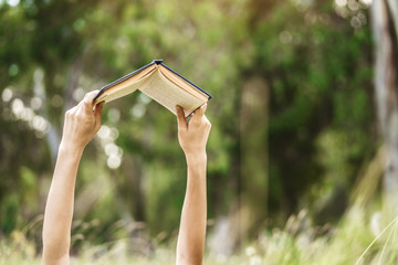 Hands raising a book up to read