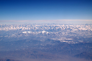 Mountains with snowy peaks on blue sky, aerial view. Planet earth natural landscape. Travel around world. Environment protection and ecology. Earth day is world birthday