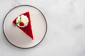 Closeup top view of raspberry cheesecake with mint leaves on white plate. Copy space.