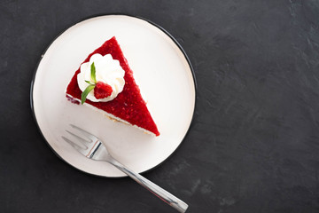 Closeup top view of raspberry cheesecake with mint leaves on white plate. Copy space.