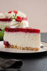 Cheesecake slice with fresh raspberries and mint leaves on a white plate. Copy space.