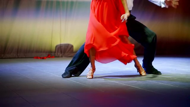 Legs of professional dancers as they dance a tango on the scene.