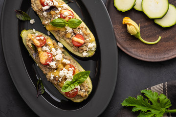 Zucchini stuffed with minced meat, cheese on a black background.Baked in oven. Copy space.