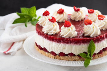 Raspberry cheesecake with whipped cream and fresh raspberries on a white plate.Copy space.