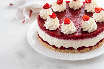 Raspberry cheesecake with whipped cream and fresh raspberries on a white plate.Copy space.