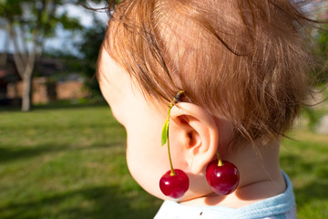 Portrait of a small baby wearing a pair of cherry earrings