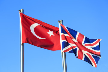 Turkish and UK flags on blue sky background