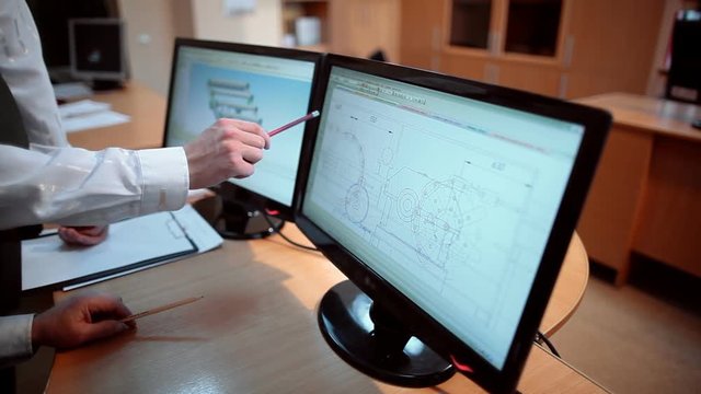 Engineers view the drawing of the part on the screen of the monitor
