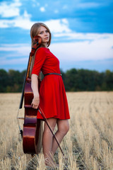 Professional female cello player in red dress with instrument outdoors