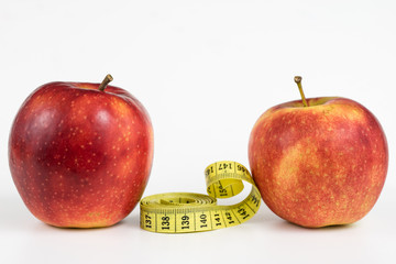 Red apples and a measure of tailor on a white table. Ripe fruits and a tailor's centimeter.