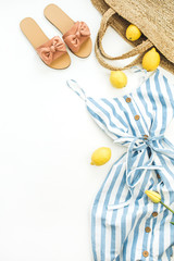 Summer female fashion stylish composition. Dress, slippers, straw, tulip flower, lemons on white background. Flat lay, top view clothes and accessories collage.