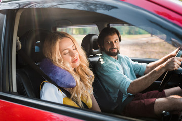 Fototapeta na wymiar girlfriend sleeping in car with traveling pillow, boyfriend driving car